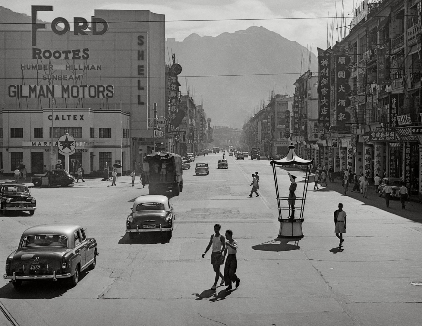 Recollection of Wan Chai, de Fan Ho — avenida de Hong Kong nos anos 1950-60, com carros antigos e letreiros de época