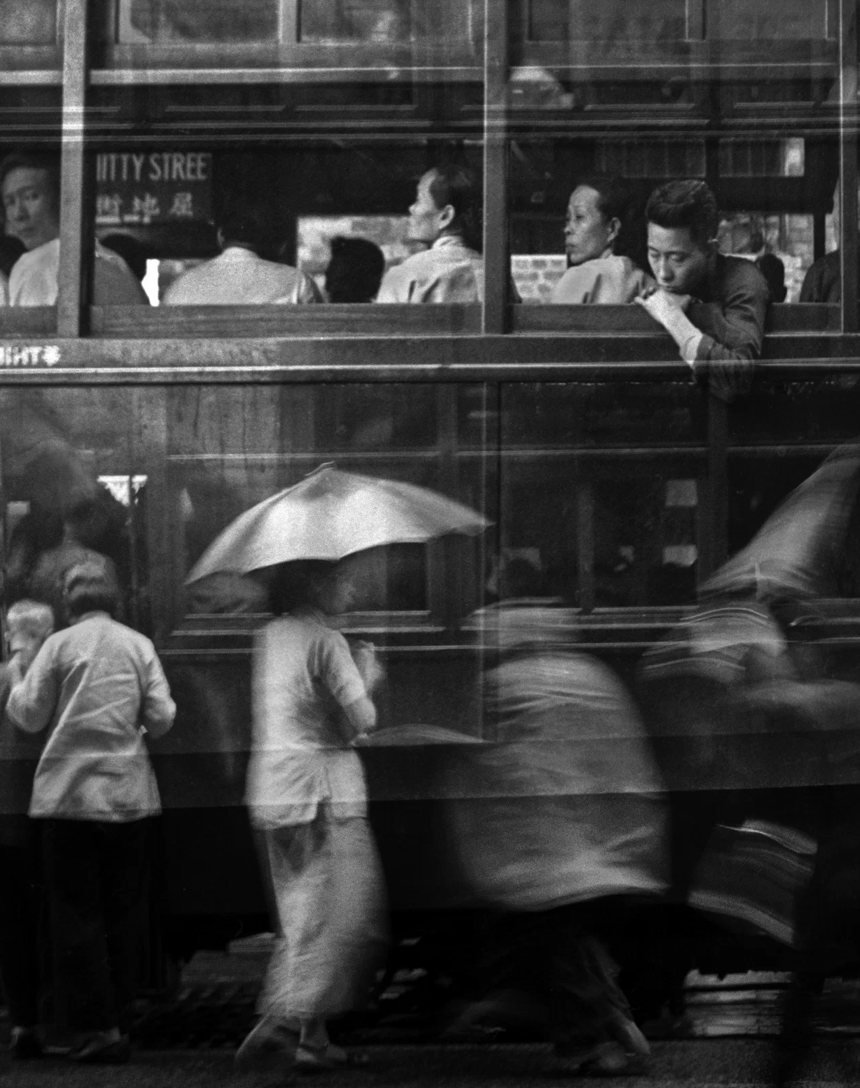 Whitty Street Diary, de Fan Ho — dupla exposição de um bonde e pedestres com guarda-chuva na Whitty Street, Hong Kong